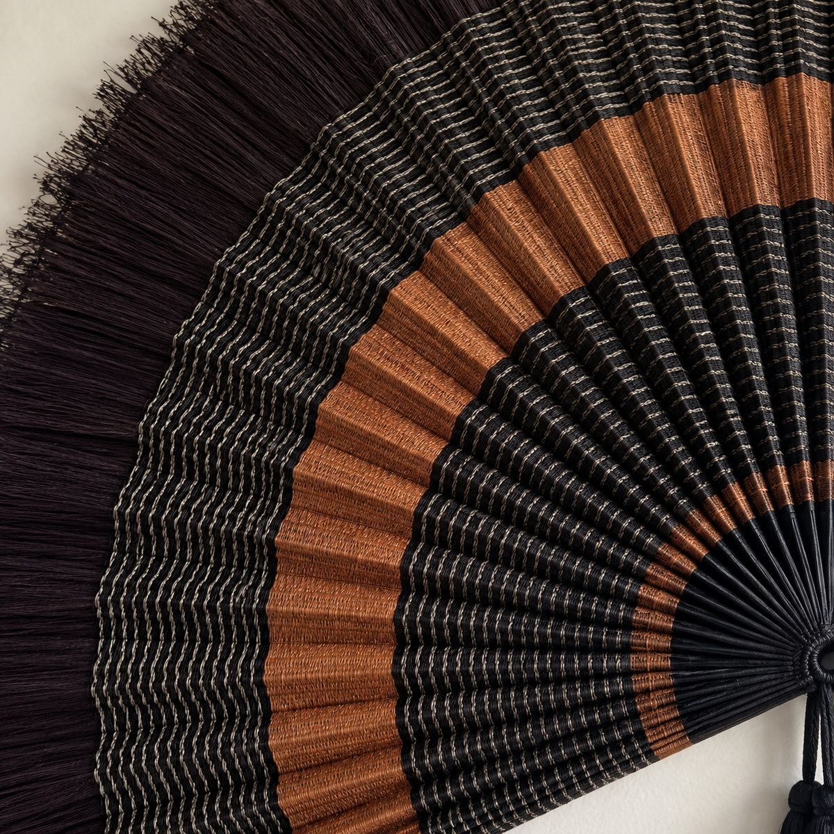 Close-up of black and copper woven bamboo fan texture and fringe